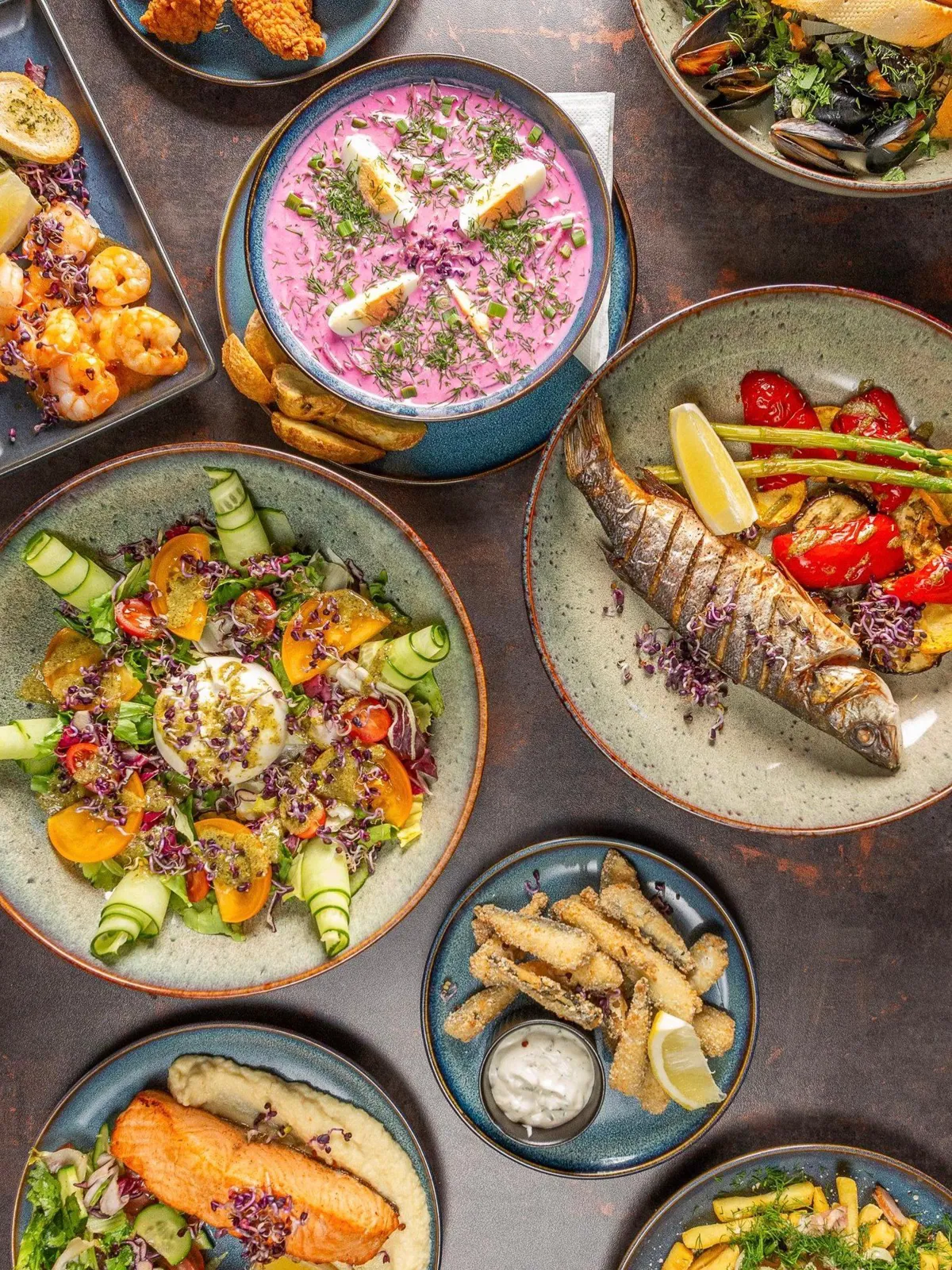 Amber Gastrobar ēdieni no augšas: salāti, cepta zivs ar dārzeņiem, aukstā zupa, garneles un mīdijas